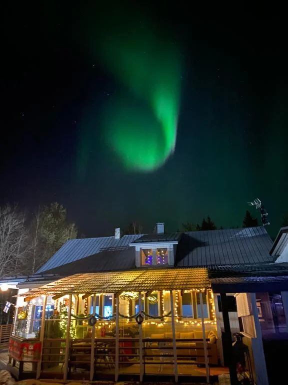 Villa Shaman cabin glowing under the Northern Lights