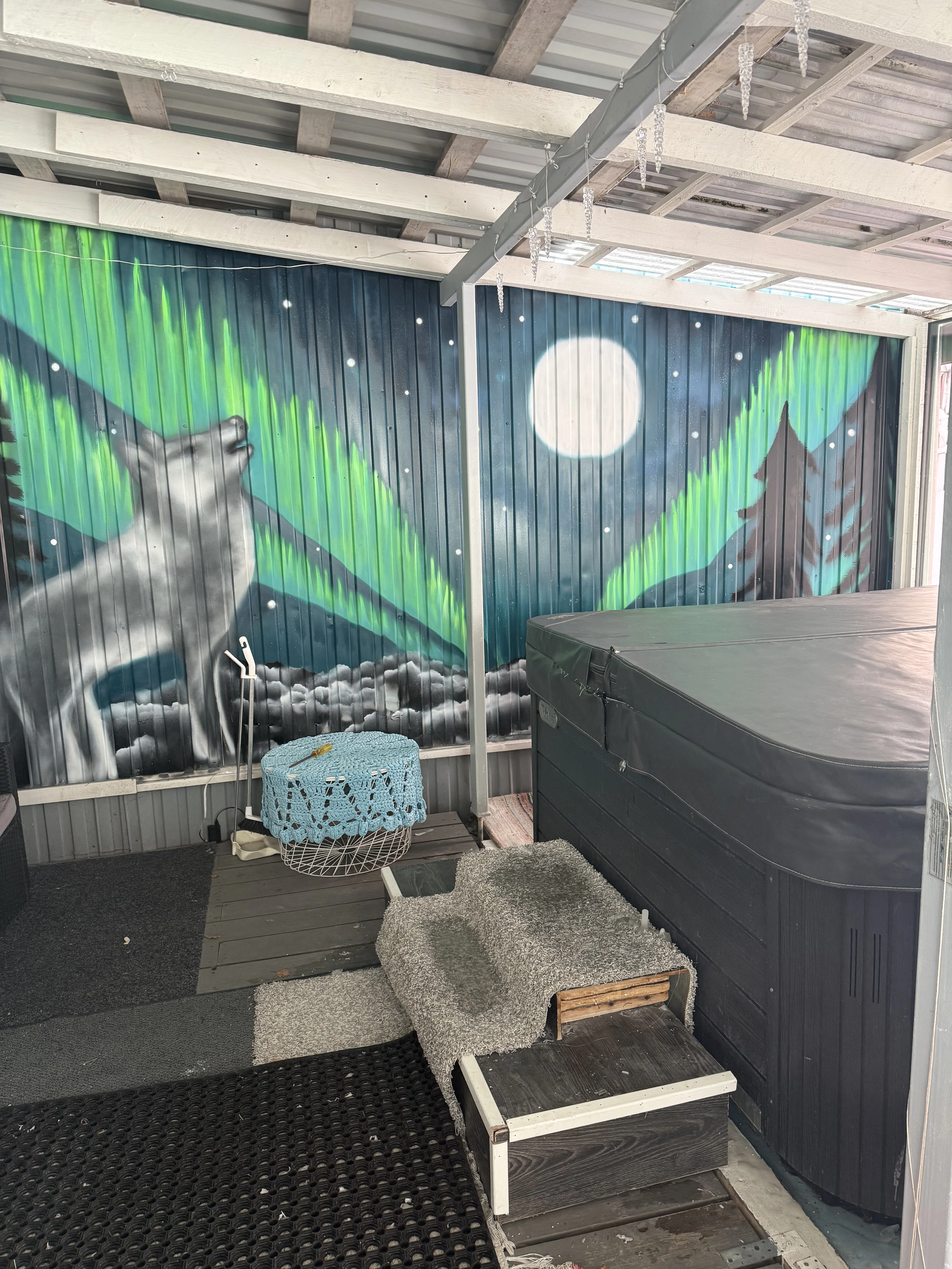 The private hot tub under a glass roof, beside a painted Northern Lights mural